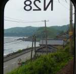 Serie 701 des Bezirks Akita - auf der Nordwest-Hauptlinie: Weite Strecken verlaufen durch wildes und einsames Gebiet dem Meer entlang. Bild aus Zug 701-28 (bezirksintern als N28 gekennzeichnet), bei Fukura, 10.Juli 2010.  