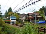 Tokyo S-Bahn, Serie 233: Der Zug mit Steuerwagen KUHA 233-63 in Ôme am Stadtrand von Tokyo. Noch stehen hier grosse Holzhäuser aus den 1950er Jahren. 23.Oktober 2011. ÔME-LINIE 