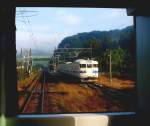 Serie 411/415: Zug mit Steuerwagen KUHA 411-515 fährt im Morgennebel aus der Haltestelle Koban Chaya im Südwesten der Südinsel Kyûshû aus. 1.Dezember 2010. (Photo durch die verglaste Führerstandrückwand eines Gegenzugs)