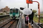 Lokalverkehr auf Shikoku - der Nordosten: Zwei Schüler sind aus Triebwagen 1509 ausgestiegen und kämpfen nun gegen Wind und Regen.