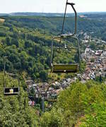 In Vianden gibt es den einzigen 1955 errichteten Sessellift Luxemburgs. Er bietet bei der Fahrt eine herrliche Panoramasicht auf das Ourtal und auf das mittelalterliche Stdchen Vianden.  31.07.2018 (Hans)

Im Jahre 2006 wurde der Viandener Sessellift komplett renoviert. Hier der Bericht eines Einheimischen: 

50 Jahre lang prgten die gelben Sessel und grnen Tragpfosten der  Veiner Slbuan  das Landschaftsbild im Stdtchen an der Our. In den vergangenen Jahren allerdings huften sich kostspielige Reparatur- und Instandsetzungsarbeiten an der beliebten Touristenattraktion. Dazu kam, dass die Anlage schon seit einiger Zeit auch nicht mehr den derzeit gltigen EU-Richtlinien entsprach.

Daher entschloss sich die Gemeinde Vianden, der die Seilbahn gehrt, die komplette Installation fr 2,1 Millionen Euro von Grund auf zu erneuern.


Nachdem im vergangenen Herbst die alten Tragmasten samt Betonsockel entfernt worden waren, begann man mit dem Gieen neuer, im Boden versenkter Fundamente fr die zwlf Pfeiler des zuknftigen Sessellifts. Auch musste die Waldschneise, durch die die Seilbahn 160 Meter hoch zur Bergstation (375 Meter . N.) fhrt, von den Gemeindearbeitern und der Forstverwaltung grndlich gelichtet werden.

Witterungsbedingt verzgerten sich allerdings all diese Arbeiten, so dass die neue Anlage nicht wie vorgesehen an Ostern, sondern erst am Wochenende des 1. Mai betriebsfertig sein wird.

Hergestellt wurden die Einzelteile des Sessellifts bei der Firma  Bartholet Metallbau AG Seilbahnen  im schweizerischen Flums. Auf einem greren Grundstck auerhalb Viandens konnten dann erst die sperrigen Batterierollen, ber die spter das Drahtseil laufen wird, zusammengebaut und mit Polizeieskorte zu ihrem definitiven Standort gebracht werden. Fr die Montage der Anlage auf dem ebenen Teilstck der rund 250 Meter langen Streckenfhrung griff man auf die Hilfe eines Krans zurck.

Wesentlich spektakulrer verlief gestern das Montieren der Tragpfosten im Hang. Hierfr wurde eigens von der Schweizer Firma Helog Heliswiss ein Puma -Helikopter angefordert, der die rund zwei bis drei Tonnen schweren Pfeiler und Batterierollen ber den Luftweg an ihren neuen Standort befrderte. Wie uns Projektleiter Franz Primc von der Gesellschaft  Enco.tec-Bartholet  erklrte, erfordern solche Manver mit Hubschrauber sowohl aus wirtschaftlicher Perspektive - eine Minute Helikoptereinsatz kostet 160 Euro - als auch aus Sicherheitsgrnden millimetergenaue Vorarbeit in puncto Sockelanfertigung. Um kein Risiko einzugehen, wurden whrend gut zwei Stunden smtliche Straen gesperrt, die sich im Bereich der Luftbrcke befanden. Einzelne der tonnenschweren Seilbahnteile wie das Laufrad der Talstation konnten jedoch nur mittels Flaschenzug und Muskelkraft montiert werden.

Die Streckenfhrung des neuen Sessellifts bleibt identisch mit der alten Route. Gleich bleibt mit einer Stckzahl von 42 auch die Zahl der silbergrauen Doppelsessel. Bei einer Geschwindigkeit von 1,5 Metern pro Sekunde wird die Auffahrt zur Bergstation auf der modernisierten Attraktion rund fnf Minuten dauern, wobei man in einer Hhe von maximal zwlf Metern ber dem Boden schweben wird. Sowohl akustisch als auch in puncto Schaukelbewegungen der Sessel verspricht die neue Anlage eine erheblich bessere Laufruhe. Angetrieben wird die Seilbahn von einem 55 Kilowatt starken Elektromotor, untersttzt im Pannenfall von einem Diesel-Notaggregat von 45 Kilowatt Leistung. Die gesamte Antriebsmechanik wurde unterirdisch installiert, so dass auch noch der Vorteil eines umfangreicheren Platzangebots beim Ein- und Ausstieg fr den neuen Sessellift spricht.

Bevor die  Veiner Slbuan  aber wieder in Betrieb geht, findet am 21. April noch eine gro angelegte Rettungsbung von Feuerwehr und Zivilschutz statt , wo es in einem simulierten Notfall gilt, binnen zwei Stunden alle Passagiere vom Sessellift zu evakuieren. Und erst nach der anschlieenden Abnahme der Anlage durch die Gewerbeinspektion darf die ffentlichkeit den Sessellift, der auch in Zukunft von der Familie Petry betrieben wird, dann wieder benutzen. Sicherlich werden viele Viandener es sich nicht entgehen lassen, bei der Jungfernfahrt ihrer neuen Seilbahn mit dabei zu sein.
