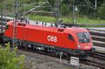Eine rote Taurus-Lok, 1116 252-6, der ÖBB, mit Güterzug, fährt am 08.09.2011 im Rangierbahnhof München Nord. Festgehalten von einer der öffentlichen Brücken. 