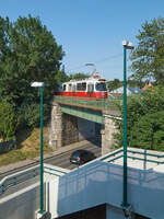 Am 29.06.2021 war ein E2-c5-Zug der Wiener Linien, bestehend aus E2 4049 und einem unbekannten Beiwagen auf dem Weg nach Rodaun. Auf der Schnellstraßenbahnstrecke im Stadtteil Mauer wird der Zug in Kürze die Haltestelle Breitenfurter Straße/ Liesingbrücke erreichen.
