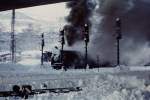 Winterdienst am 16. Dezember 1976 im Bahnhof Bludens mit einer Dampfschneeschleuder von Henschel, geschoben von einer 1020. Der von einem Schneepflug zusammengeschobene Schnee wurde in hohem Bogen aus dem Gleisbereich befördert.