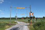 Ein typischer ländlicher Bahnübergang in Schweden. Am Holzbalken ist die Höhenkontolle für die Oberleitung befestigt. Die Lichtzeichnenanlage mit dem Andreaskreuz hängt auch an einem Holzbalken. Beachtesnwert ist auch, dass zwischen den Gleisen Holzbohlen liegen. 
Hier fahren die Züge mit annähernd 100 Stundenkilometern, so in Deutschland fast undenkbar.
Aufgenommen am 30.06.2022 irgendwo in Südschweden.