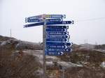 Hier an der Grenze beginnen der schwedische Rallarvgen, 40 km bis Abisko, und der norwegische Rallarveien, 14 km bis Rombaksbotn. Auf der schwedischen Seite sind alle Stationen angegeben, auch die, die nicht mehr bedient werden, nur Riksgrnsen (1 km)nicht, auf der norwegischen Seite nur die End-km ohne Ortsangabe. Rechts ist ein Teil der Lokschuppen-Ruine vom schwedischen Grenz-BW zu sehen.