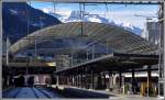 Bahnhof Chur mit Glasdach über dem Postautodeck und die Berge des Safientals mit Piz Fes.