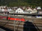 Der Schatten des Aussichtsturmes reicht weit, aber bevor er das Bahnhofsgebude erreichen knnte, geht die Sonne hinter den Bergen unter. Vorne fhrt noch 185 114-6 entlang... (Erstfeld, 1.10.2011) 