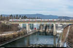 Ein unbekannter RV-Dosto ist am 28. Februar 2018 auf dem Flugzug von Basel nach Zürich Flughafen unterwegs und überquert beim Kraftwerk Wettingen die Limmat. Im Hintergrund rechts der Zugspitze ist zudem ein DTZ zu erkennen, der als S6 Uetikon - Baden vom Furttal her in Kürze Wettingen erreichen wird.