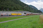 Samstag den 22.07.2023 um 16:47 Uhr am Gotthard-Basistunnel Nordportal. Die linke Röhre ist die Oströhre (in der Regel für den Nord-Südverkehr), während die rechte Röhre, die Weströhre (in der Regel für den Süd-Nordverkehr) benützt wird. Hinter der Oströhre an der Mauer entlang führt die alte Strecke von Altdorf über Erstfeld nach Göschenen. Während das Gleis vorne an der Weströhre die alte Strecke von Göschenen über Erstfeld nach Altdorf ist. Die Tunnellänge des GBT beträgt 57,1 km. Die Ansicht zum Portal ist in Nord- Südrichtung. Vom Norden her einfahrender Güterzug in die Oströhre. Während von Göschenen her über die alte Route ein Reisezug in Richtung Altdorf folgt. Bei dem Bild geht es ausnahmsweise nicht um die Züge sondern um die Vorstellungskraft was es bedeutet während bis zu 12 Minuten (bei Güterzügen noch länger) sich in einem Tunnel zu befinden. Ohne sich klar zu werden ob die Dunkelheit jemals endet. Da ich diesen Tunnel schon oft befahren habe, und dabei Ortsfremde Reisende (vor allem aus dem Ausland) immer wieder beobachten kann wie sie etwas Unruhig werden wen nach zirka 10 Minuten immer noch kein Tageslicht zu erblicken ist, dann ist es schon beeindruckend was da geschaffen wurde. Wer das Buch „Der Tunnel“ von Friedrich Dürrenmatt (1952) oder „Der Tunnel“ von Hans Leister welcher in seinem Buch den Gotthard-Basis-Tunnel meint und die Handlung darin sogar in diesem Tunnel stattfindet, der versteht vielleicht meinen  Grund für diese Aufnahme. Hans Leister verweist dabei sogar auf die Ausgabe von Dürrenmatt aus dem Jahre 1952. Der versteht vielleicht den Grund für das Bild. Aber eben, erst wen man mindestens eines der Bücher oder sogar beide gelesen hat. Leider sind die Portale nicht so schön wie die alten Portale. Es gibt auch einen technischen Grund dafür. Koordinaten GMS (Grad, Minuten, Sekunden): N 46° 50’ 11.9’’ O 8° 38’ 43.8’’