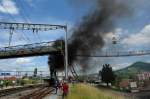 125 Jahre Gotthardbahn - Eine mchtige schwarze Rauchwolke steigt in den blauen Frhlingshimmel und zeigt weithin sichtbar an, hier wird noch mit Dampf gefahren. Im Vordergrund die Transportseilbahn des hiesigen Tonwerks. Frick (Aargau) am 31.5.2007