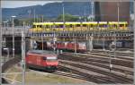 Re 460 013-8 und einige Re 420 warten auf neue Aufgaben und auf der Münchensteinerstrasse überquert ein Be 6/10 Tango der BLT die Geleise beim Bahnhof Basel SBB.