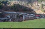 Am 5. Januar 2016 fährt eine Re 4/4 II mit IR 2324 Locarno - Basel SBB über die Intschireussbrücke oberhalb Amsteg. Auf dem Bild zu sehen sind ausserdem die Gotthardautobahn sowie die Kantonsstrasse, alles auf engstem Raum in das Tal gequetscht.