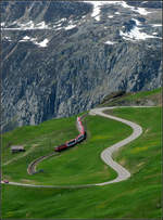 Geschlängelte Verkehrswege -     Glacier-Express zwischen Nätschen und Andermatt schlängelt sich ins Tal hinunter, während ein einsames Auto die kurvenreiche Straße zum