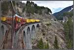 IR1148 nach Chur führt am Zugschluss drei Postcontainer mit, hier beim Überqueren des Schmittentobels. Im Hintergrund ist noch das Landwasserviadukt zu sehen. (17.04.2019)