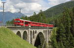 Mit dem Steuerwagen 1758 vorraus fährt R1937 (Scuol-Tarasp - Pontresina) über das Inn-Viadukt bei Cinuos-chel-Brail. Hinten schiebt Ge 4/4 613  Domat/Ems .

Cinuos-chel-Brail, 15. Juni 2017