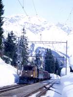 RhB Extra-GmP 3031 Landquart - Davos Platz vom 14.03.1999 Einfahrt in Davos - Laret mit Lok Ge 6/6I 414 - B 2246 - D 4052II - 5568 - 5593 - 5082 - 6610 - 7070. Hinweis: Winterstimmung pur, man beachte mal die Schneehhe, zum Vergleich das blaue Stationsschild rechts.