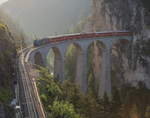 Die Sonne ist gerade aufgegangen, da schiebt sich Ge 4/4 III 652  Vaz/Obervaz  Lenzerheide-Valbella  mit dem R 1114 (St.Moritz - Chur) aus dem Landwassertunnel auf das Landwasserviadukt.