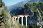 RhB Schnellzug 560 von St.Moritz nach Chur am 24.10.1997 auf Landwasser-Viadukt zwischen Filisur und Alvaneu mit E-Lok Ge 4/4 III 645 - B 2444 - AB 1522 - A 1226 - B 2392 - B 2357 - B 2376 - D 4221 - Z 13091. Hinweis: diese berhmte Fotostelle bietet Ende Oktober nur kurze Zeit gute Lichtverhltnisse. Aufnahme entstand ca. 15:10h, wie zu erkennen ist, liegt die Felswand noch im Schatten! Aber der Viadukt ist bereits wieder im Vollschatten zur Sommerzeit ab ca. 17:10h, zur Winterzeit vor 16:10h. Gute Fotos mit Planschnellzge Richtung Chur sind nur 1 oder 2 Aufnahmen mglich! gescanntes Dia.
