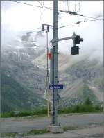 Multifunktionsfahrleitungsmast auf Alp Grm mit Stationsschild, Erdungsstange, Abfertigungssignal etc.Im Hintergrund ist der Palgletscher erkennbar, der frher bis in die Talsohle reichte. (05.06.2007)