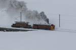 Die Dampfschneeschleuder Xrotd 9213 und das Bernina-Krokodil fahren am 23.02.2013 dem Lago Bianco entlang und werden in Krze Ospizio Bernina erreichen.