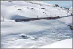 Blick von der Passstrasse auf den BerninaExpress 972 mit den ABe 4/4 III 55  Diavolezza  und 54  Hakone . Der BEX972 hat soeben die Station Ospizio Bernina verlassen und fhrt entlang des halbleeren Lago Bianco Richtung St.Moritz. (18.04.2013)