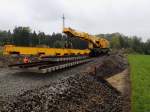 Gleisbaukran-KRC1200_99819119002-9 setzt die herantransportierte Weiche bei trüben, regnerischem Herbstwetter exakt bei der Gleisbaustelle ab; 151016