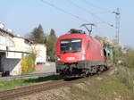 1116 142 beschleunigt mit einem aus leeren Autotransportwagen bestehenden Güterzug aus der Langsamfahrstelle zwischen Bruckmühl und Westerham auf der Mangfalltalbahn heraus.