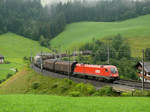 Eine 1116 zieht einen gemischten Güterzug die Steigung bei Unterwindau hoch in Richtung Brixen.