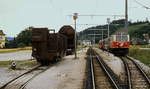 1099 013-3 der Mariazellerbahn im Juni 1991 im Bahnhof Klangen, auf dem Ladegleis sind ein Güterwagen und ein aufgebockter Normalspur-Schotterwagen abgestellt