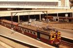 Ein Vorortzug mit Triebwagen 1647 im November 1976 im Bahnhof Johannesburg. Im Hintergrund das Empfangsgebäude. Damals herrschte in Südafrika noch die Apartheid/Rassentrennnung und dieser Gebäudeteil durfte nur von  Weißen  betreten werden, der für  Farbige  bestimmte Teil war wesentlich einfacher gehalten. Besonders Reisende mit der Bahn wurden ständig mit den Folgen der Apartheid konfrontiert. Das reichte von vier getrennten Toiletten (Männer/Frauen,  whites / non whites ) auch auf kleinen Bahnhöfen bis zur Fahrt während des nachmittäglichen Berufsverkehrs: Die Wagen für  whites  waren noch einmal zu einem Viertel gefüllt, während der für  non whites  reservierte Zugteil überfüllt war und einige bei geöffneten Türen auf den Trittbrettern mitfuhren...