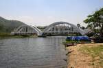 Die 1919 fertiggestellte 87,3m lange Tha Chomphu Bridge über den Mae Nam Tha, von den Einheimischen Saphan Khao (=Weiße Brücke) genannt, gilt als eines der Wahrzeichen der Provinz Lamphun und ist deshalb ein Touristen-Hotspot mit Parkplatz, Informationsstand, Parkanlage und sogar mit einer Treppe auf den Bahndamm. Bild vom 22.März 2023.