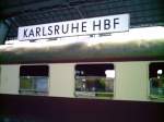  Wagen im Vordergrund und dahinter das Bahnhofsschild des Karlsruher ...
