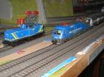 Modellbahn von Christian Maier MWB V 100 und der MWB Taurus bei einer Doppelausfahrt aus dem Bahnhof. im Hintergrund steht die 216 029 mit einem F-Zug im Bahnhof.