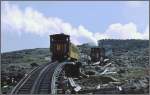 Mount Washington Cog Railway Schon �ber der Waldgrenze, inmitten einer Ger�llhalde, befindet sich die obere Ausweichstelle Skyline Siding. Zwei Loks mit zwei Wagen haben in dem Gleisstumpen Platz und warten auf die beiden Gegenz�ge. Das Umlegen einer Weiche dauert ein wenig, denn es m�ssen 12 Einzelteile umgestellt werden. V�llig untypisch f�r die USA werden ausgewechselte Schwellen, Balken und anderes Material einfach neben dem Geleise liegengelassen, sodass man st�ndig das Gef�hl hat, man befahre eine Entsorgungsdeponie. Lok 3 'Agiocochok' (Baujahr 1883) und Lok 6 'Kancamagus' (1874) in der Skyline Siding. (Archiv 02.08.1998)