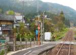 lokalverkehr---ehemstaatsbahn-und-jr-west Der KIHA 120-202 der Kuzury�-Linie - ein Spiegel-Bild: In Ushigahara h�lt der Wagen vor einer Bauernhausgruppe mit B�umen voller Kakifrucht. 3.November 2008.