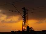 Ein Fahrleitungsmast im Licht des Sonnenuntergangs am Gemmenicher Weg in ...
