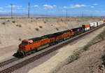 Westwärts fahrender Güterzug in der Nähe der Grenze Arizona/Kalifornien in einem Einschnitt, über den eine Strassenüberführung führt. Needles, CA, 30.9.2022