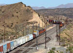 BNSF trifft BNSF auf der Passhöhe Cajon Pass: gemischter Güterzug begegnet Containerzug in der Nachmittagssonne.