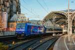 SRI/Rail Invest 146 520-2 mit RE1-Verstärker bei der Ausfahrt in Köln Hbf, November 2025.