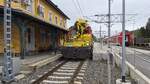 Turmwagen X552 der ÖBB-Infra neben dem Bahnhofsgebäude Wies-Eibiswald. Am 29. April 2026 geduldet sich dieser 'Farbtupfer' bei einem Halt zeigenden Signal auf die weitere Verschubfahrt: