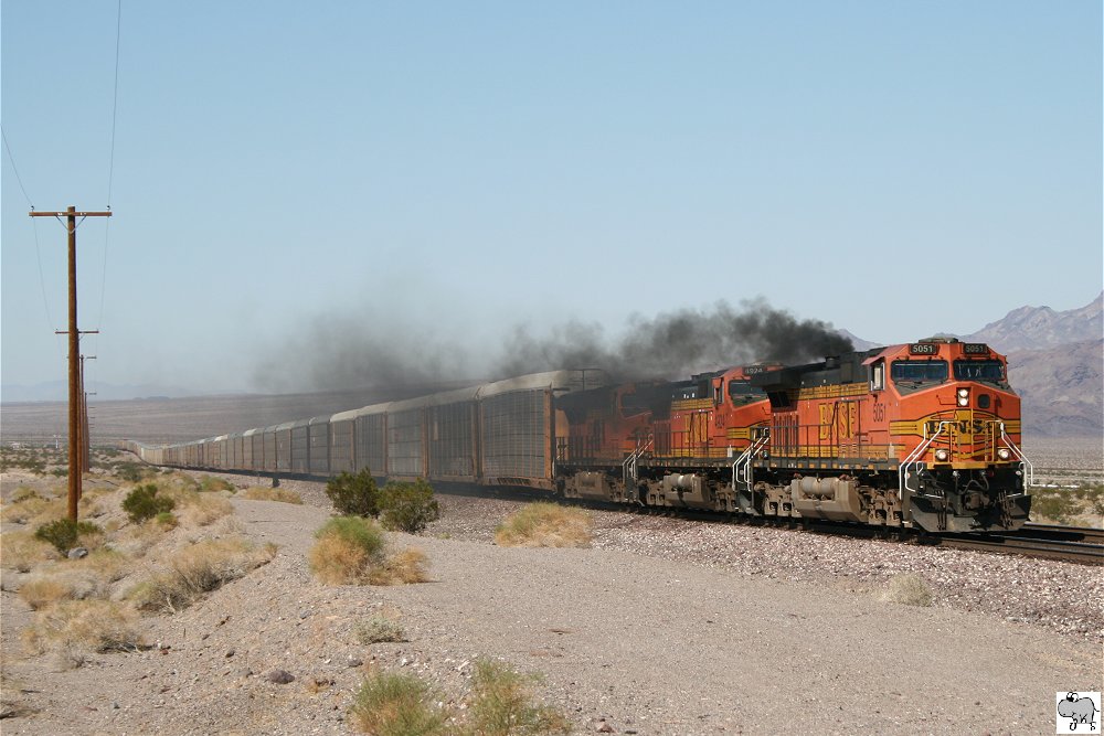# 5051 (C44-9W), # 4924 (C44-9W), # 7866 (ES44DC) der BNSF ziehen einen Autotransportzug durch die kalifornische Wste. Lok # 5051 versucht sich derweil als Dampflok. USA, 26. September 2011.