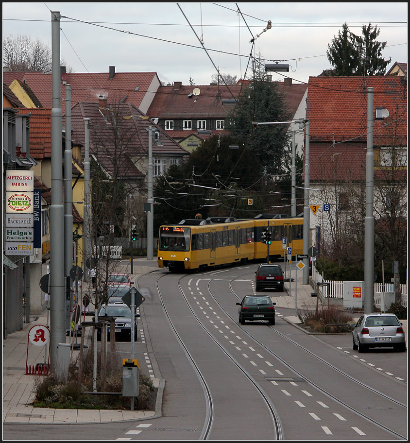 . Straßenbündig - 

In der engen Ortsdurchfahrt von Stuttgart-Stammheim müssen sich Stadtbahn und Autos die Straße teilen. Platz für einen eigenen Bahnkörper gab es hier nicht und ein Tunnel wäre zu aufwändig gewesen. Blick von der Haltestelle  Korntaler Straße  nach Norden. 

11.12.2011 (M)