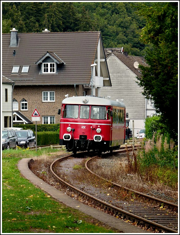 - Zu Besuch bei der Oleftalbahn - Der Trassenverlauf der Oleftalbahn ist historisch typisch f�r die kosteng�nstige Anlage von Nebenbahnen unmittelbar an und auf vorhandenen Stra�en- und Wegetrassen, auf eisenbahntechnisch aufw�ndige Kunstbauten konnte so weitestgehend verzichtet und die Baukosten niedriger gehalten werden. Der stra�ennahe Verlauf bedingt unz�hlige Stra�enquerungen, unbeschrankte und beschrankte Bahn�berg�nge und die �berfahrt �ber den Olefer Dorfplatz. Durch diese weitestgehend erhaltene typische Anlage als Nebenbahn ist die Oleftalbahn-Strecke ein unverwechselbares und einmaliges Zeugnis der Eisenbahngeschichte in Deutschland. Daher l�uft aktuell ein Verfahren, die Oleftalbahn-Strecke unter Denkmalschutz zu stellen. Hier verl�sst der MAN Schienenbus die Haltestelle Olef in Richtung Nierfeld. 28.08.2011 (Jeanny) 