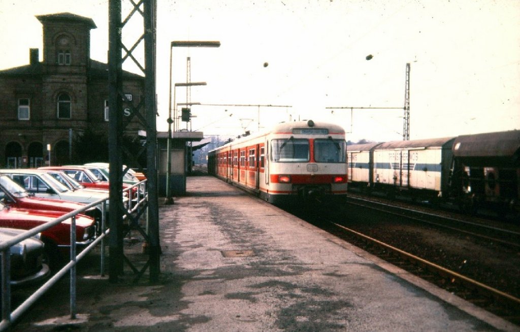 01.03.1981 Hattingen Hbf S3 nach Oberhausen ...

Aufgrund des hohen Alters des Bildes und der damals benutzten Technik ist dieses Bild nat�rlich nicht allererste Sahne. Dennoch m�chte ich es nicht vorenthalten weil vieles heute bereits Geschichte ist und sich kaum jemand noch daran erinnern kann...

v.l.n.r. der alte Bahnhof noch mit Bahnsteigdach, Der S-Bahntriebwagen der ersten Generation, die vollst�ndig vorhandene Oberleitung und der in Hattingen gebildete auch an Wochenenden verkehrende gemischte G�terzug nach Hagen, zusammengestellt von den damals noch reichlich vorhandenen Gleisanschl�ssen in und um Hattingen, ... Einen ganzen Tag war die 260 261 damit besch�ftigt alle Wagen aus den Anschl�ssen zusammenzuziehen. Mit anbei waren Rolltreppen von O+K, K�hlwagen der Heinrich Hill AG, St�ckg�ter aus Hattingen und Sprockh�vel, Stahlprodukte und Maschinen, einzeln laufende Tankwagen, ausgebesserte Personenwagen, Zementwagen und vieles mehr...
Ein absolut modellbahntauglicher Zug, gezogen von einer 216 ab und an auch von einer 221 ...

Ber�chtigt war dieser Zug auch da er sehr oft �berl�nge hatte...
Zweimal gefahren wurde nicht, Alles musste ran an den Zug.
Hinten stand er am Grenzzeichen, vorne gerne mal 50 Meter weiter und hinter dem Signal.
(die Gleise im Bahnhof haben Hauptbahnl�nge)
Der Lokf�hrer war oft gezwungen seine Maschine zu verlassen und bei Wind und Wetter im freien zu verharren bis er Fahrt frei bekam... Das konnte schon mal ne Stunde dauern...
Grund war die Stra�enbr�cke welche das Formsignal bedeckte, ...

Heutzutage ein Unding, ... Damals normal ...
