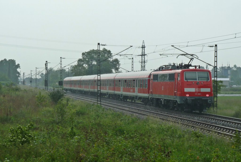 111 061 mit einer RB nach Offenburg am verregneten 24.05.12 kurz vor dem Halt in Buggingen. Im Bahnhof steht 146 114-4 mit dem Gegenzug nach Neuenburg (Baden).