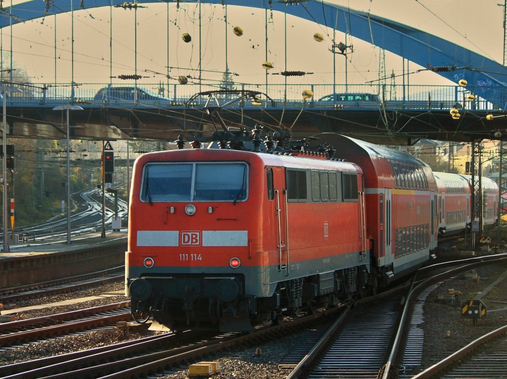 111 114 schiebt den RE4 am 29.11.2011 im Zickzack-Kurs unter der Burtscheider Brcke aus Aachen Hbf. Links im Bild die Sdrampe, die zum Buschtunnel und weiter nach Belgien fhrt.