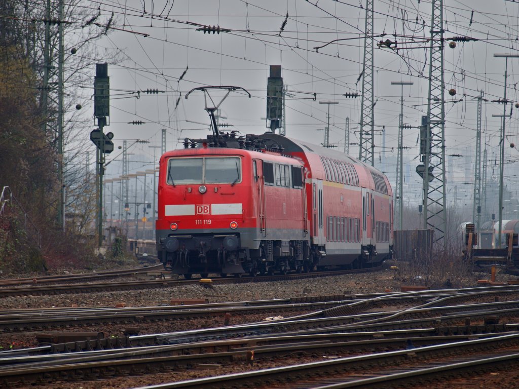 111 119 schiebt am 20.02.2011 den RE4 in den dunstverhangenen Westbahnhof in Aachen.