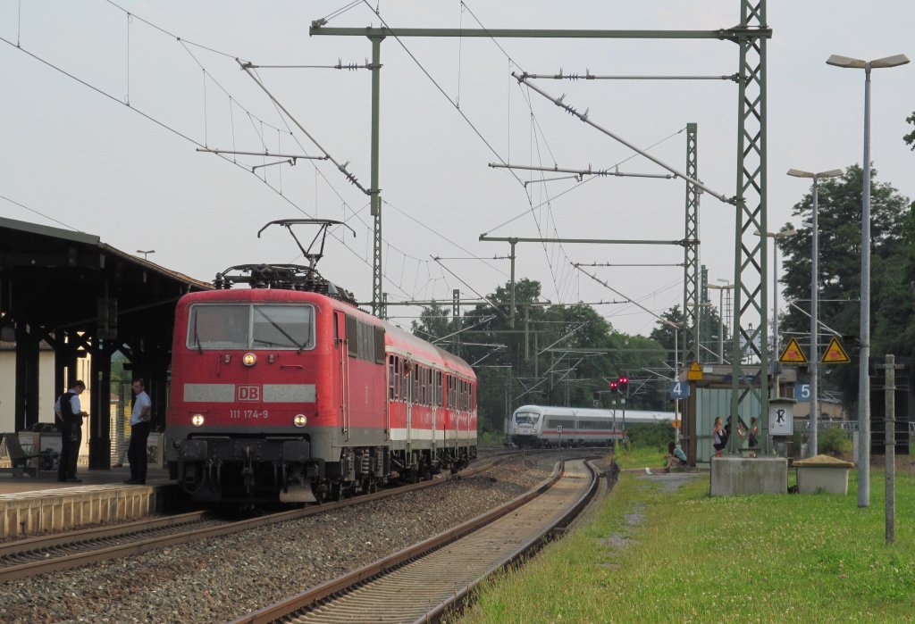 111 174-9 wartet am 27. Juli 2012 mit ihrer Regionalbahn nach Ludwigsstadt auf die berholung durch ICE 1104 in Kronach, der sich im Hintergrund schon nhert.