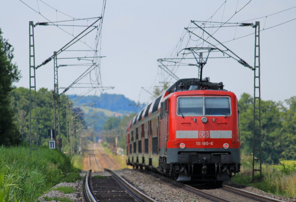 111 180-6 war am 14. Juli 2013 an einem Mnchen-Salzburg-Express, hier zu sehen beim B Weisham. Im Hintergrund ist der nchste Halt, Prien am Chiemsee zu sehen.